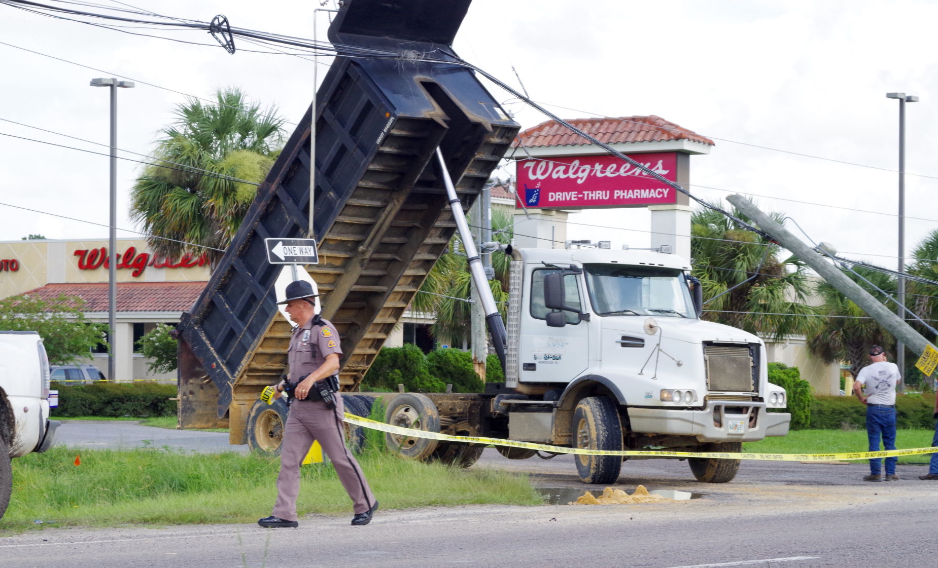Dump truck snags overhead utility lines leaving construction site